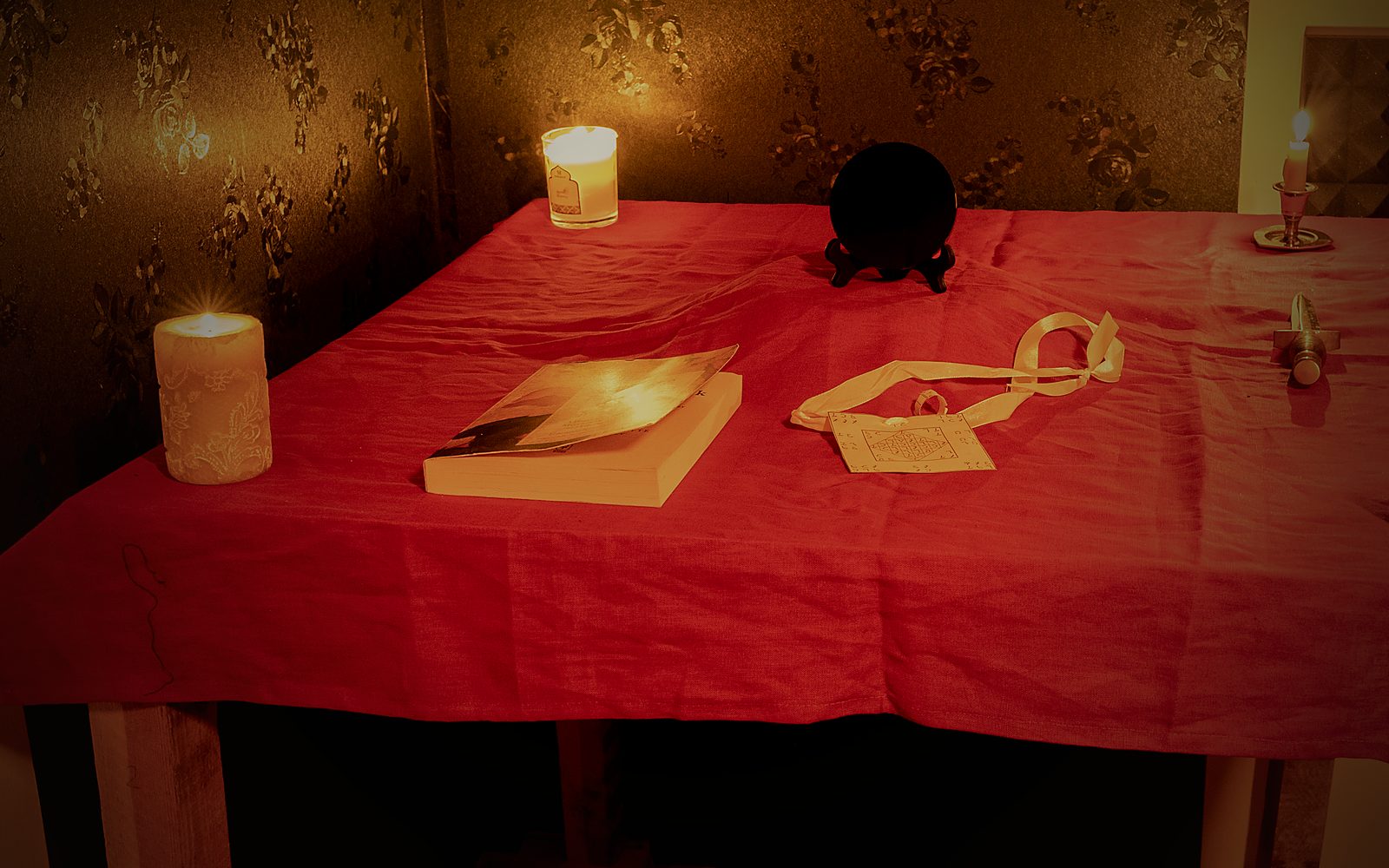 The full working setup on the Holy Table by candlelight: the scrying mirror on its stand, the seal and cord, and hand-poured candles burning